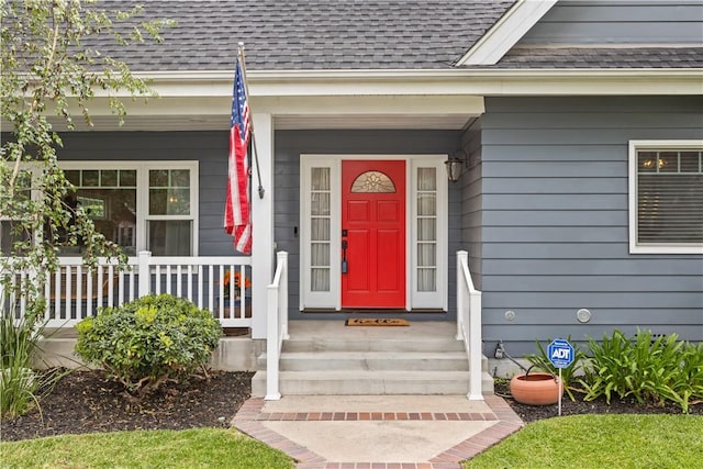 property entrance with roof with shingles and a porch