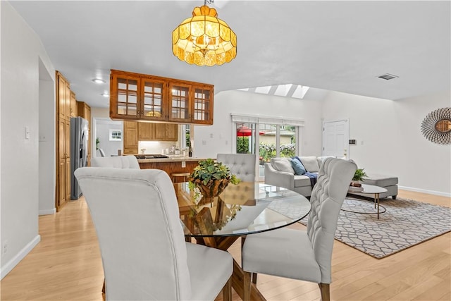 dining space with baseboards, a skylight, visible vents, and light wood-type flooring