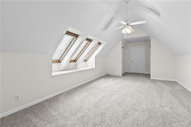 additional living space with a ceiling fan, lofted ceiling with skylight, and carpet