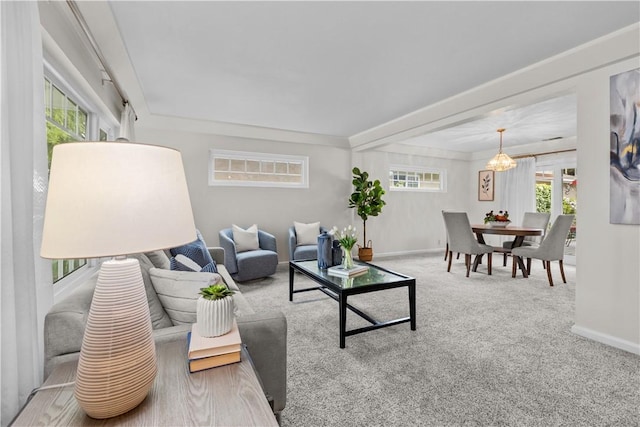 carpeted living room with baseboards and a notable chandelier