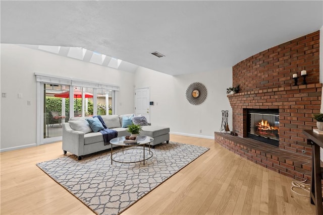 living area with visible vents, baseboards, vaulted ceiling, and wood finished floors