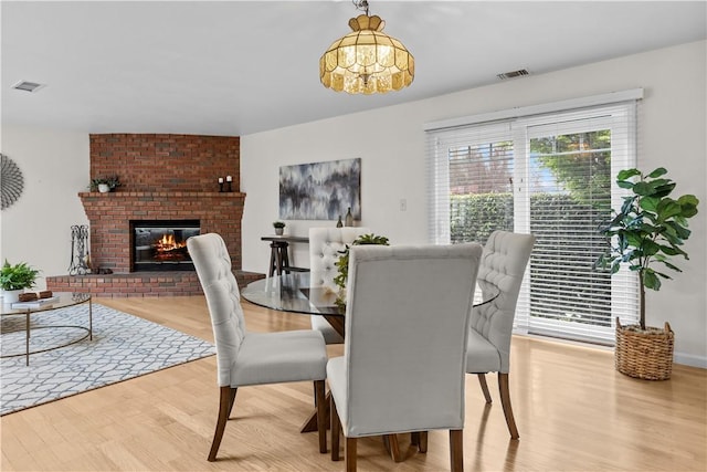 dining room with visible vents, a fireplace, wood finished floors, and an inviting chandelier