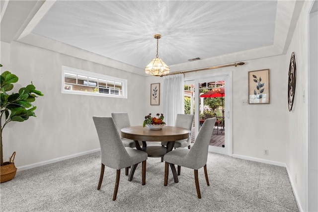 carpeted dining room with baseboards, visible vents, a raised ceiling, and a healthy amount of sunlight