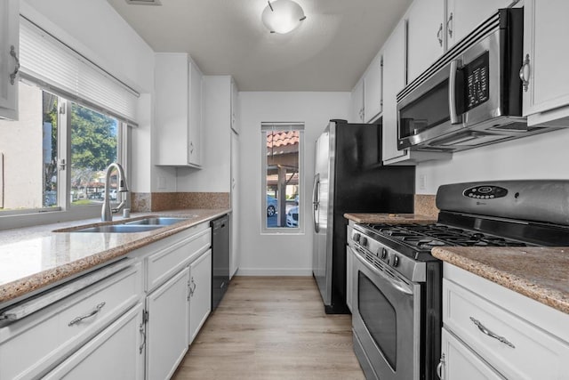 10774 Dabney Dr Unit 17, San Diego, CA 92126 - kitchen with appliances with stainless steel finishes, a sink, white cabinets, light wood finished floors, and light stone countertops