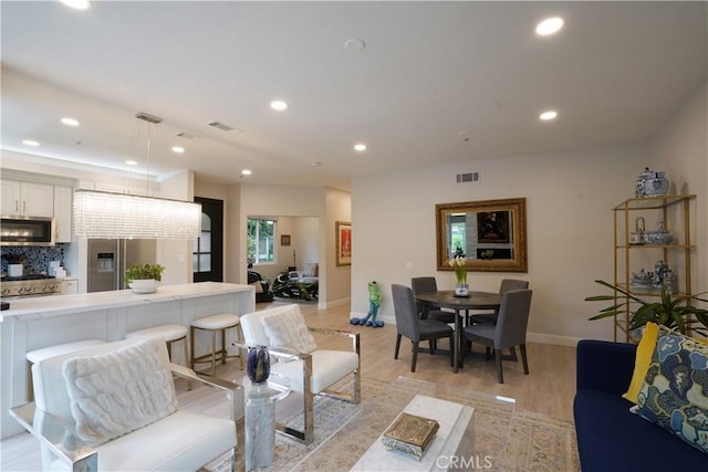 living area with recessed lighting, baseboards, visible vents, and light wood-type flooring
