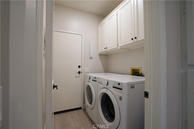 clothes washing area featuring washer and dryer, cabinet space, and light wood-type flooring