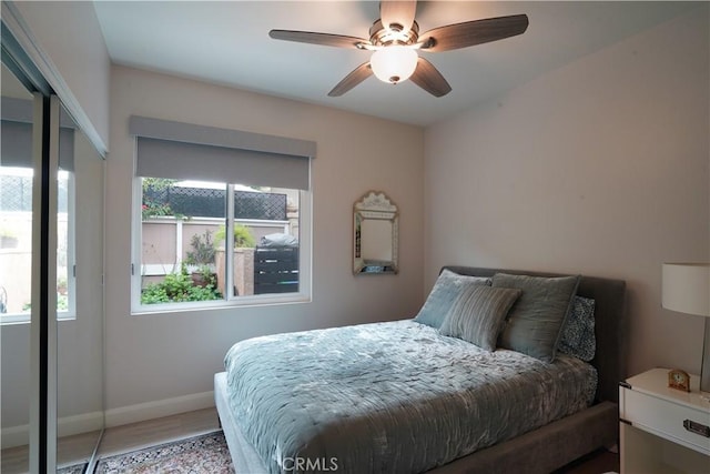 bedroom with baseboards, wood finished floors, ceiling fan, and multiple windows