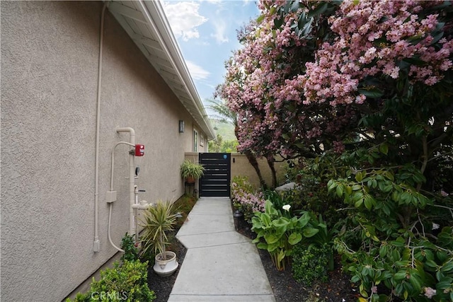 view of side of home with stucco siding and fence