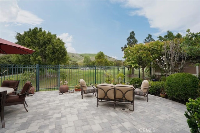 view of patio with fence, an outdoor living space, and a mountain view