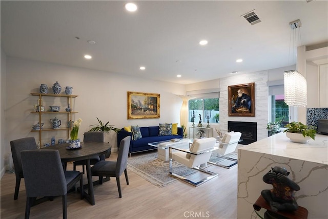 dining space featuring recessed lighting, visible vents, a fireplace, and light wood-style floors