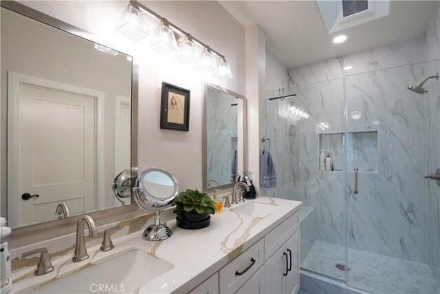 full bath featuring visible vents, a marble finish shower, a sink, and double vanity