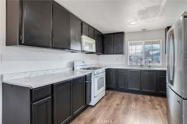 16117 Sweetaire Ave, Lancaster, CA 93535 - kitchen with white appliances, a sink, light wood-style flooring, and light countertops