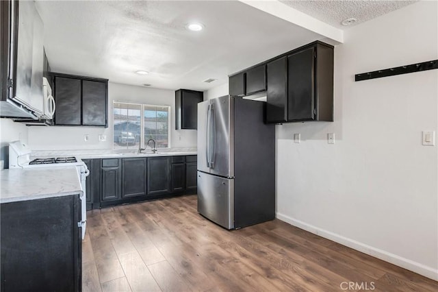 16117 Sweetaire Ave, Lancaster, CA 93535 - kitchen featuring white appliances, wood finished floors, light countertops, a textured ceiling, and baseboards
