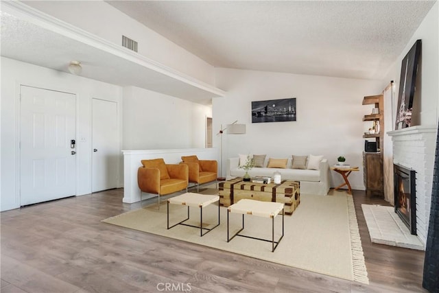16117 Sweetaire Ave, Lancaster, CA 93535 - living area with vaulted ceiling, a fireplace, wood finished floors, and a textured ceiling