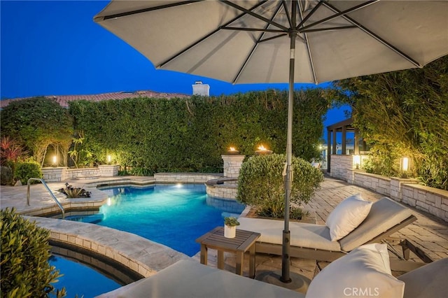 pool at night featuring a fenced in pool and a patio