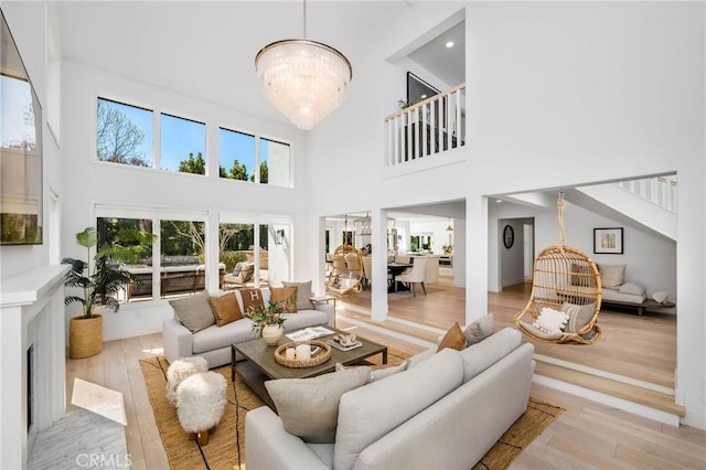 living room featuring a chandelier, a high ceiling, and light wood finished floors