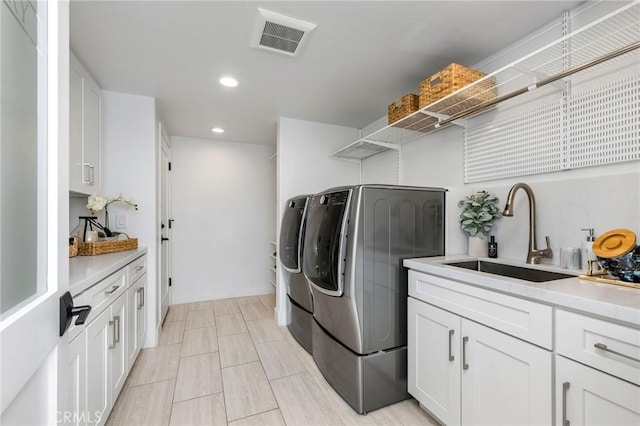 washroom with recessed lighting, visible vents, a sink, separate washer and dryer, and cabinet space