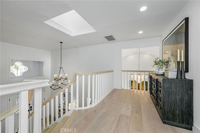 hallway with recessed lighting, visible vents, a skylight, a chandelier, and light wood-style flooring