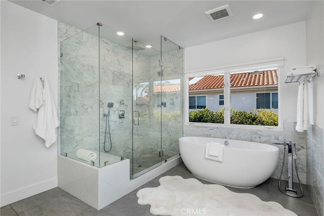 bathroom featuring tile patterned flooring, a marble finish shower, a freestanding tub, and visible vents