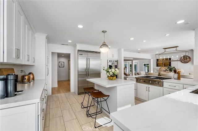 kitchen featuring white cabinetry, stainless steel appliances, a kitchen island, and recessed lighting