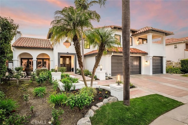 mediterranean / spanish house featuring a tiled roof, driveway, french doors, and stucco siding
