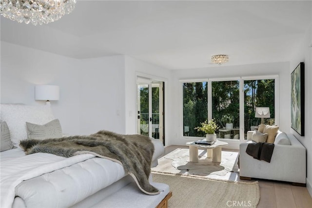 bedroom with an inviting chandelier, access to outside, and light wood finished floors