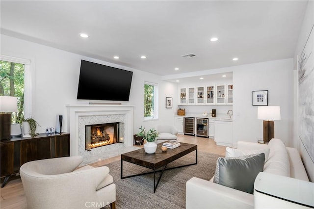 living room with light wood-type flooring, bar area, beverage cooler, and visible vents