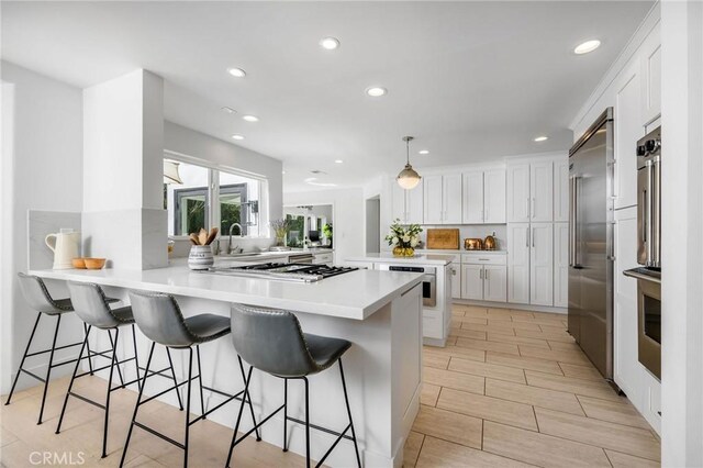 kitchen with a peninsula, a kitchen bar, white cabinets, and recessed lighting