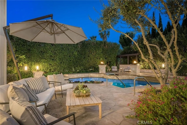 pool at night with a patio area, a fenced in pool, and an outdoor living space