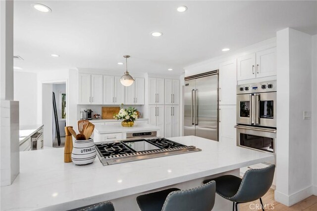 kitchen with a kitchen bar, a peninsula, white cabinetry, and stainless steel appliances