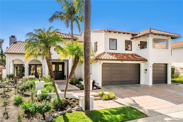 mediterranean / spanish house with stucco siding, concrete driveway, a tiled roof, and a garage