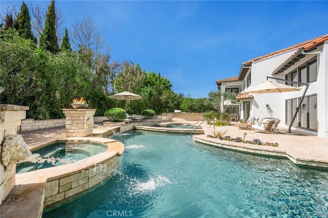 view of swimming pool featuring a pool with connected hot tub and a patio