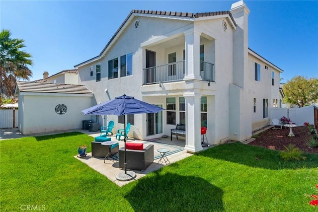 back of house with a balcony, a fenced backyard, a yard, a patio, and stucco siding