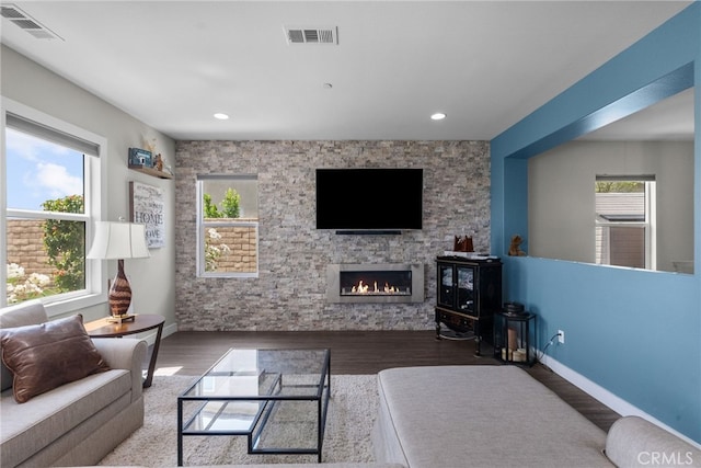 living room with a fireplace, wood finished floors, visible vents, and baseboards