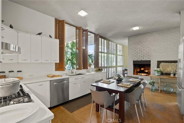 799 Hillview Way, Chico, CA 95926 - kitchen featuring stainless steel dishwasher, extractor fan, light countertops, white cabinetry, and a brick fireplace
