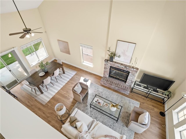 1523 E Pryor Dr, Fresno, CA 93720 - living area with a high ceiling, wood finished floors, baseboards, a brick fireplace, and ceiling fan