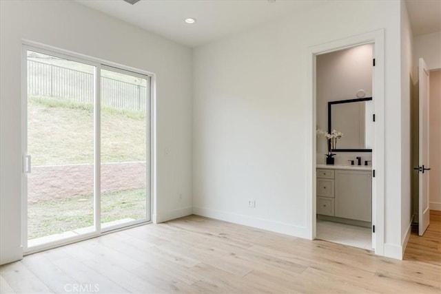 unfurnished bedroom with light wood-style floors, baseboards, multiple windows, and access to exterior