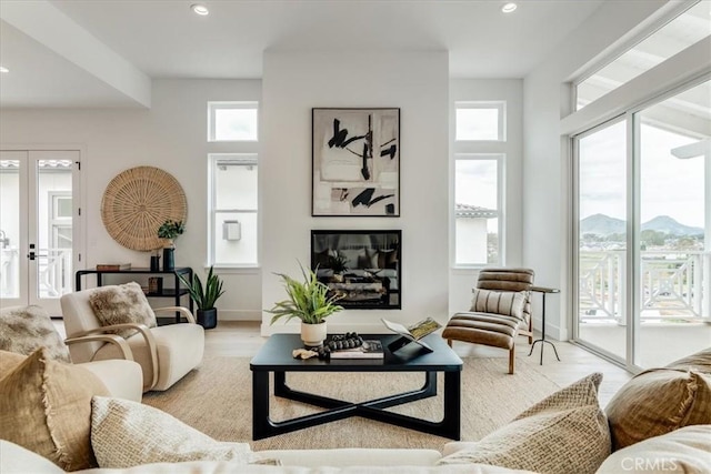 living room featuring baseboards, light wood-type flooring, recessed lighting, a mountain view, and french doors