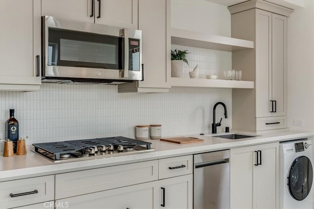 kitchen featuring washer / clothes dryer, open shelves, appliances with stainless steel finishes, and light countertops