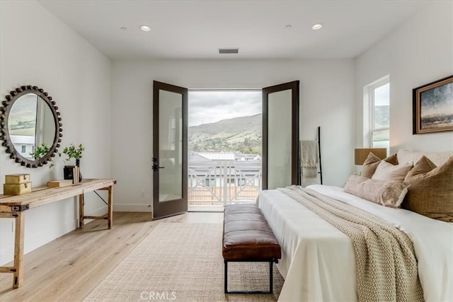 bedroom featuring access to exterior, visible vents, light wood-type flooring, a mountain view, and recessed lighting
