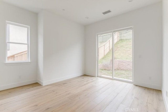 spare room with baseboards, wood finished floors, and visible vents