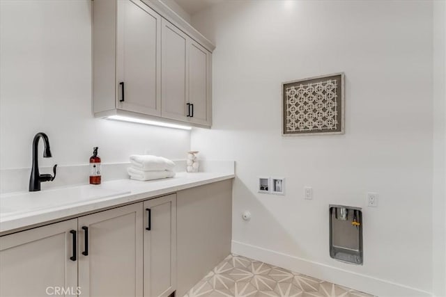laundry area with cabinet space, washer hookup, a sink, baseboards, and hookup for a gas dryer