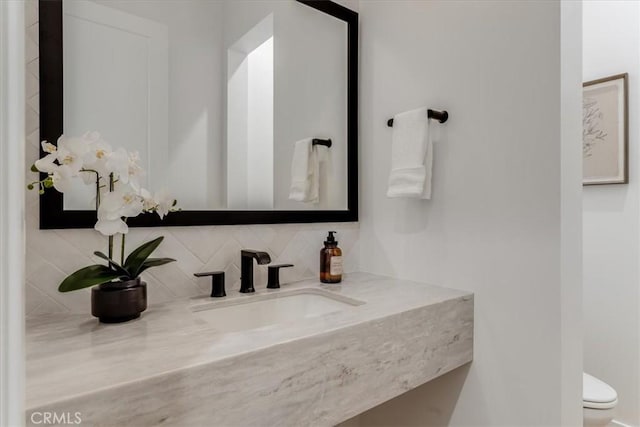 bathroom featuring vanity, decorative backsplash, and toilet