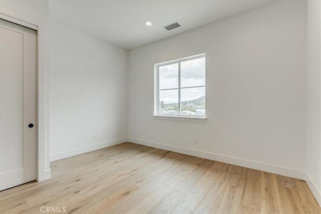 empty room featuring visible vents, recessed lighting, light wood finished floors, and baseboards