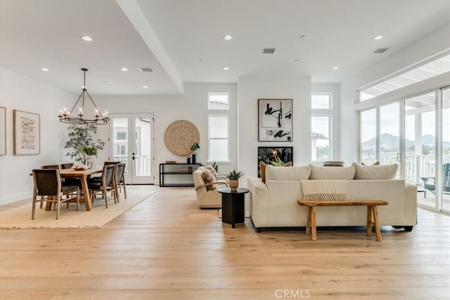 living room with an inviting chandelier, visible vents, and light wood-style floors
