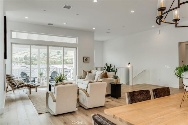 living area featuring light wood-style floors, visible vents, recessed lighting, and a chandelier