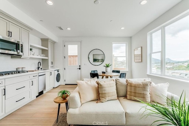 living room with recessed lighting, washer / dryer, visible vents, and light wood-type flooring