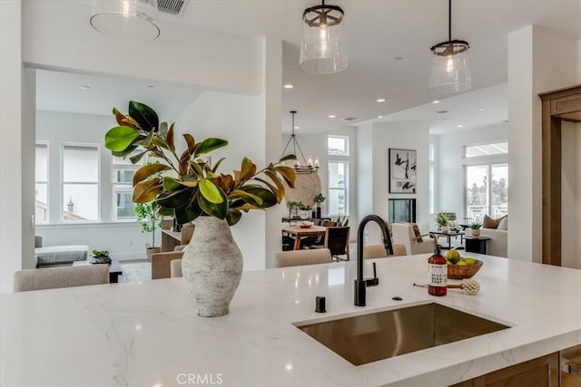 kitchen featuring a sink, light stone countertops, open floor plan, and visible vents