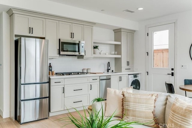 kitchen featuring visible vents, open shelves, washer / dryer, appliances with stainless steel finishes, and backsplash