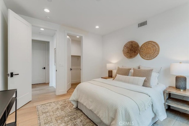 bedroom with recessed lighting, visible vents, a walk in closet, and light wood-style floors